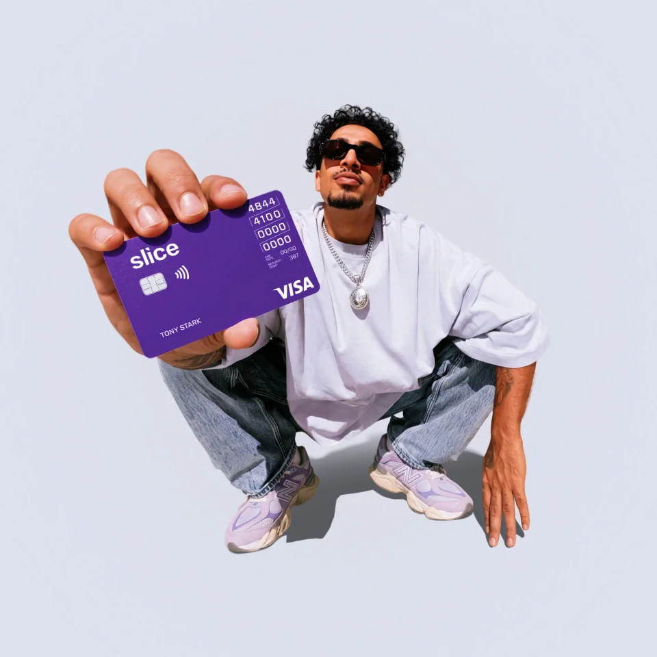 Man crouching and holding out a purple Slice Visa card toward the camera